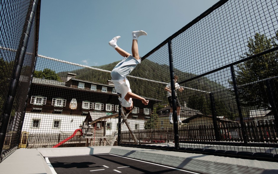 Familienfreundliche Trampolinanlage im Freien, auf der Kinder aktiv Spaß haben mit Blick auf die Berge