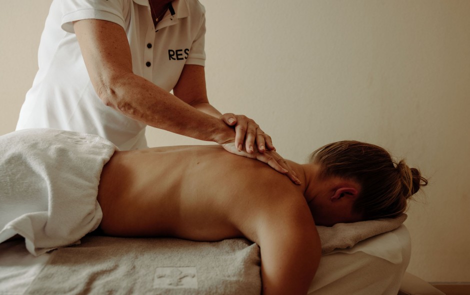 Gast erhält eine wohltuende Rückenmassage im Wellnessbereich des Hotel Resl Resort in Flachau