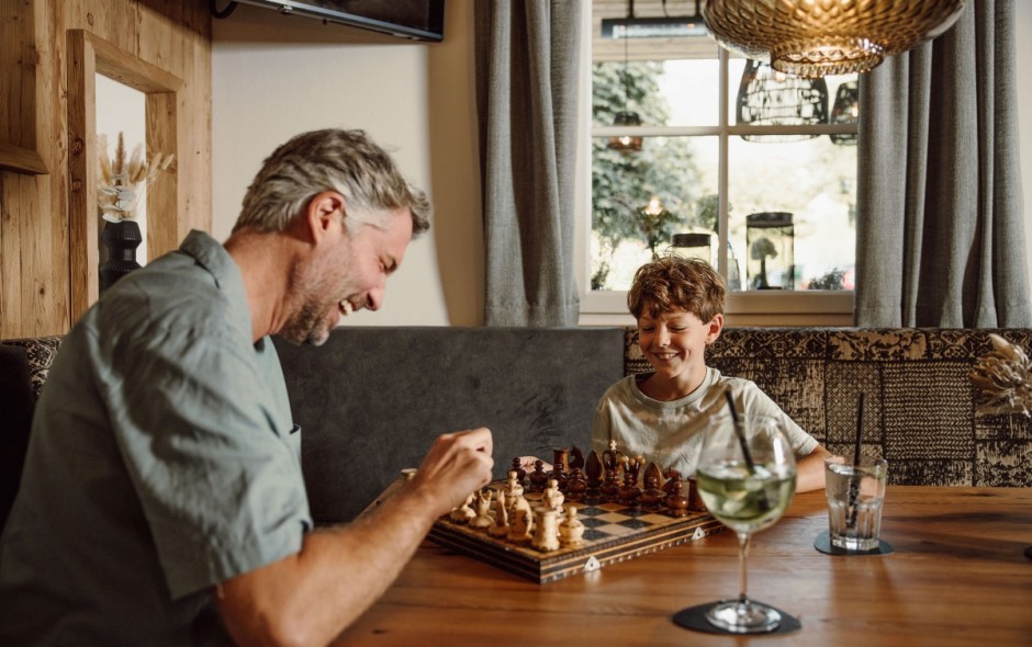 Vater und Sohn spielen Schach im gemütlichen Restaurantbereich des Hotel Resl Resort in Flachau