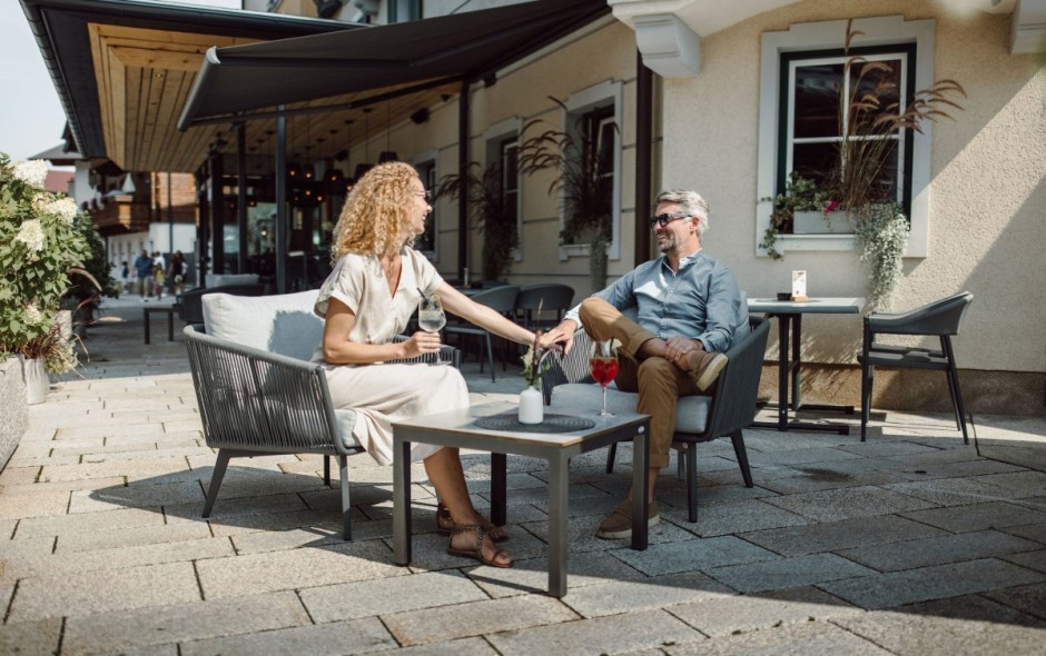 Paar sitzt entspannt im Außenbereich des Hotel Resl Resort in Flachau und genießt die Sonne im Urlaub